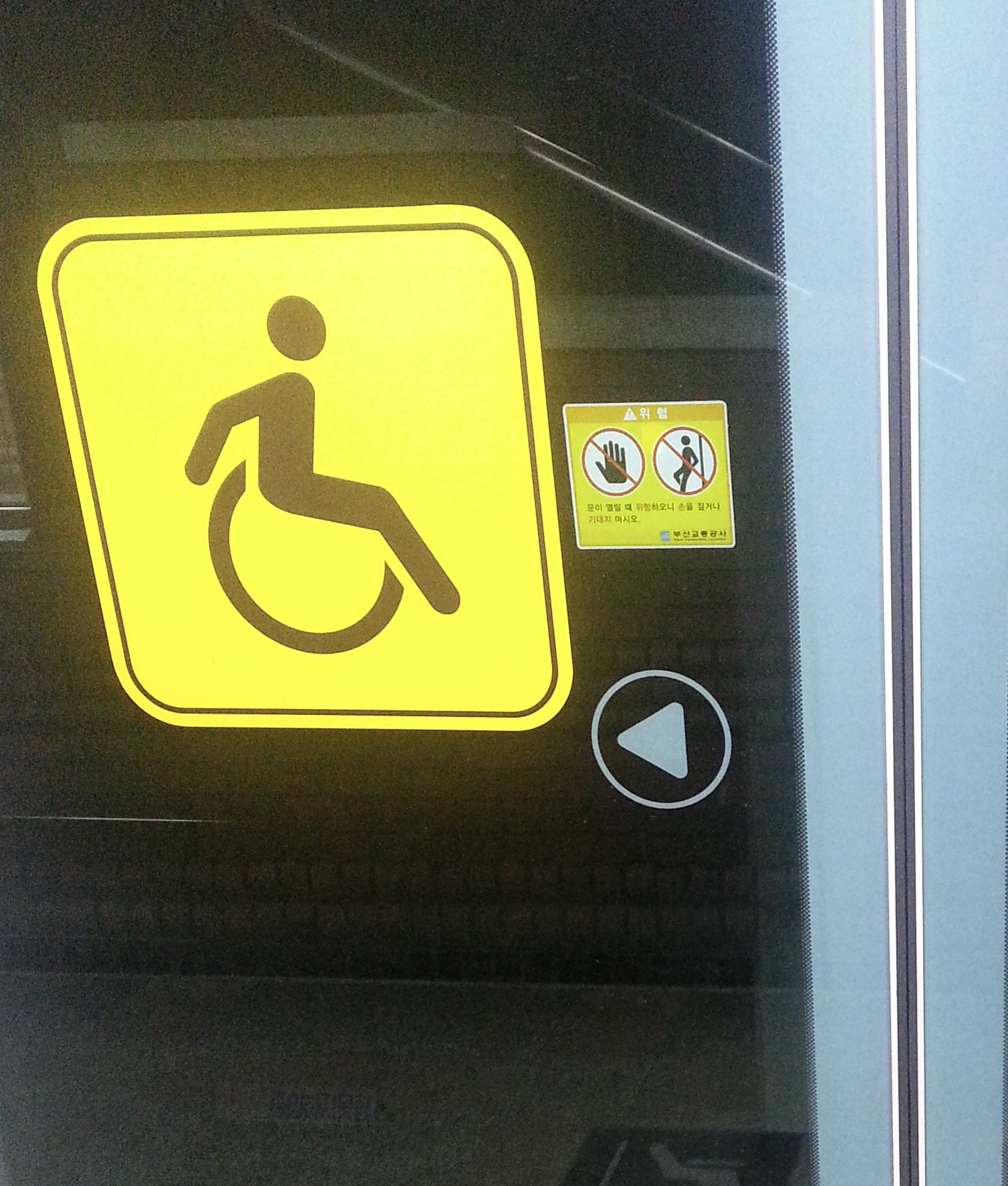 黄色で車いすマーク。手で車いすをこいでいる様子をピクトグラムにしている。